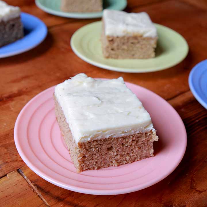 A piece of Keto spice cake on a pink plate with more pieces of cake in the background