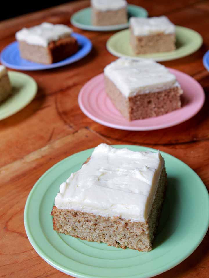 A piece of Keto spice cake on a green plate with more pieces of cake in the background