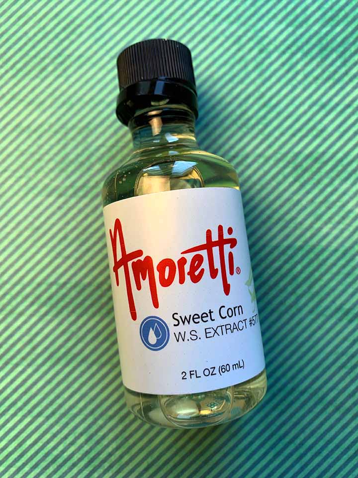 a bottle of Amoretti Sweet Corn Extract against a green striped background