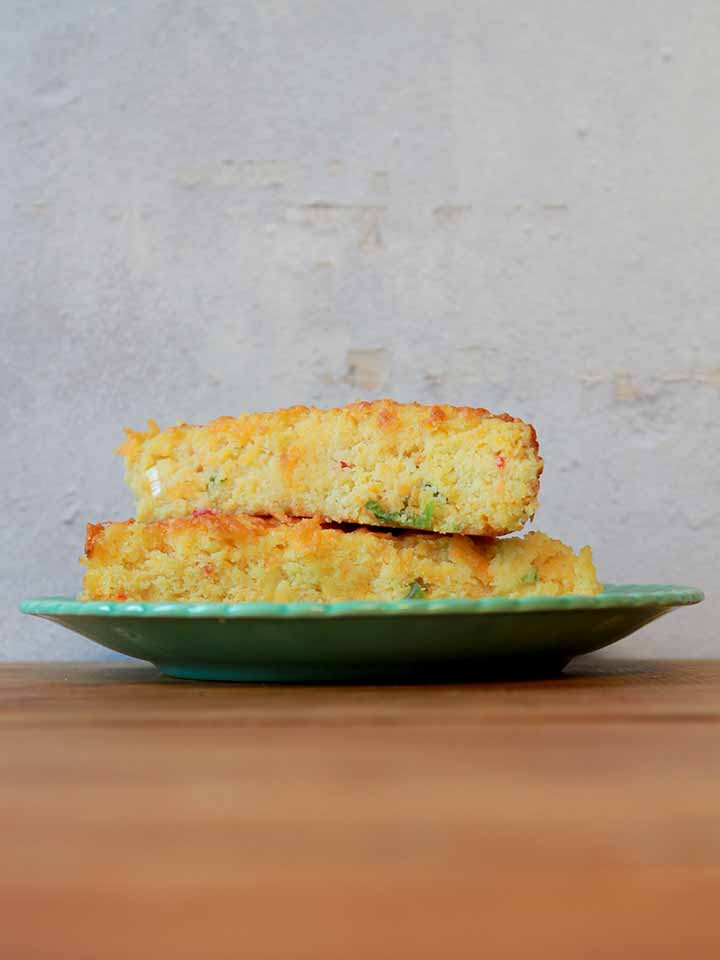 a stack of low carb Keto cheesy cornbread on a green plate on a wooden tabletop