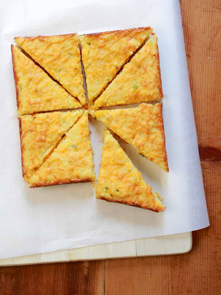 a top down view of 8 slices of low carb cheesy jalapeno cornbread against a white background