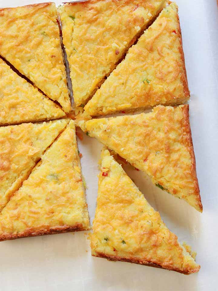 a top down view of 8 slices of low carb cheesy jalapeno cornbread against a white background