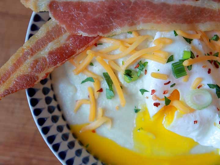 a close up of paleo cheese grits with a poached egg and bacon