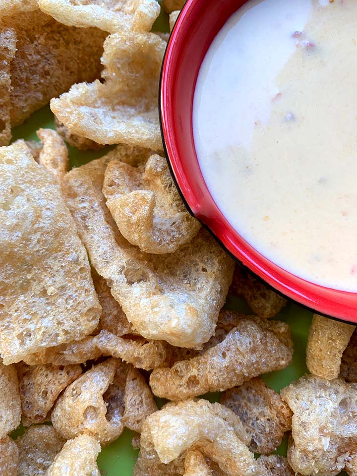 a close up of a red bowl filled with Keto queso and pork rinds