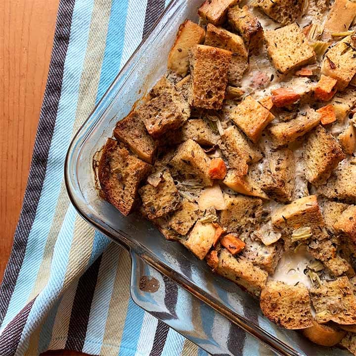 a casserole dish filled with Keto stuffing against a striped towel