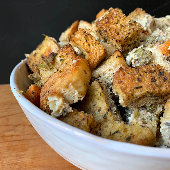 a side view of a white bowl holding Keto Thanksgiving Stuffing against a black background