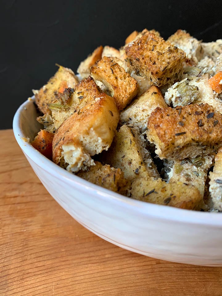 a side view of a white bowl holding Keto Thanksgiving Stuffing against a black background