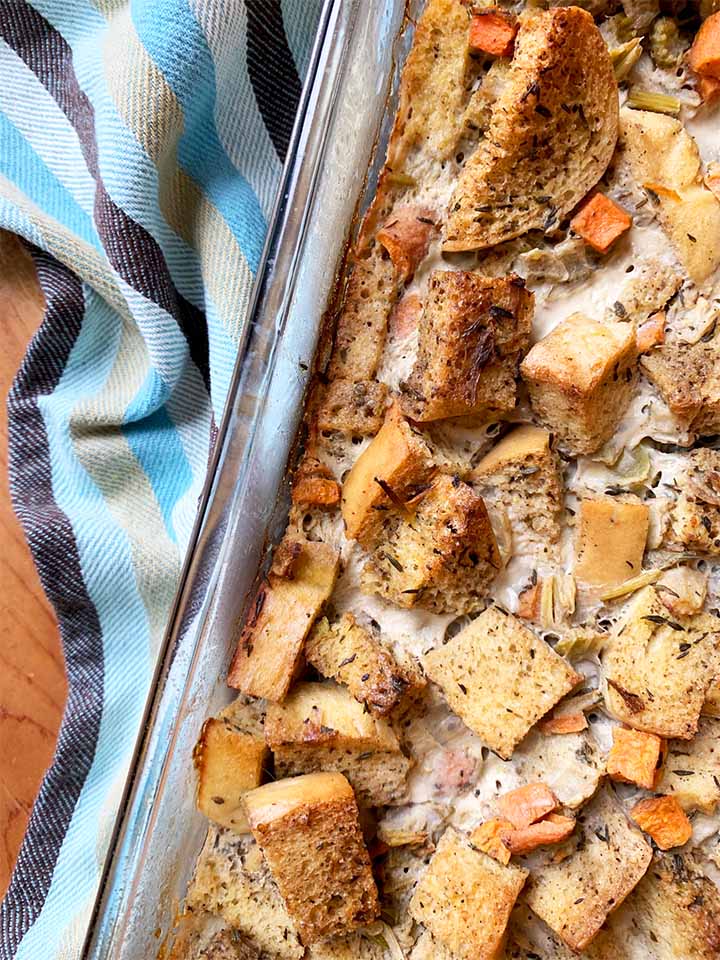 a casserole dish filled with Keto stuffing against a striped towel