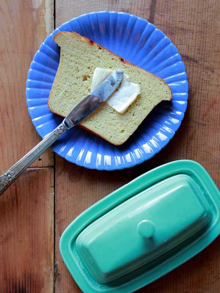 a knife spreads butter on a slice of Keto sandwich bread.