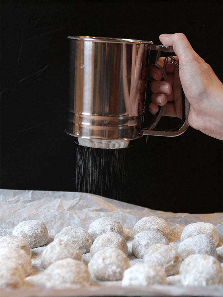 a hand sifted powdered sweetener onto gluten free Snowball Cookies