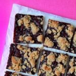 a top down view of blueberry crumble bars against a hot pink background