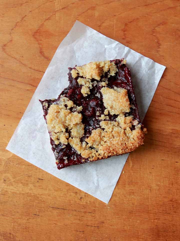 a top down view of a gluten-free blueberry crumble bar with a bite taken out of it
