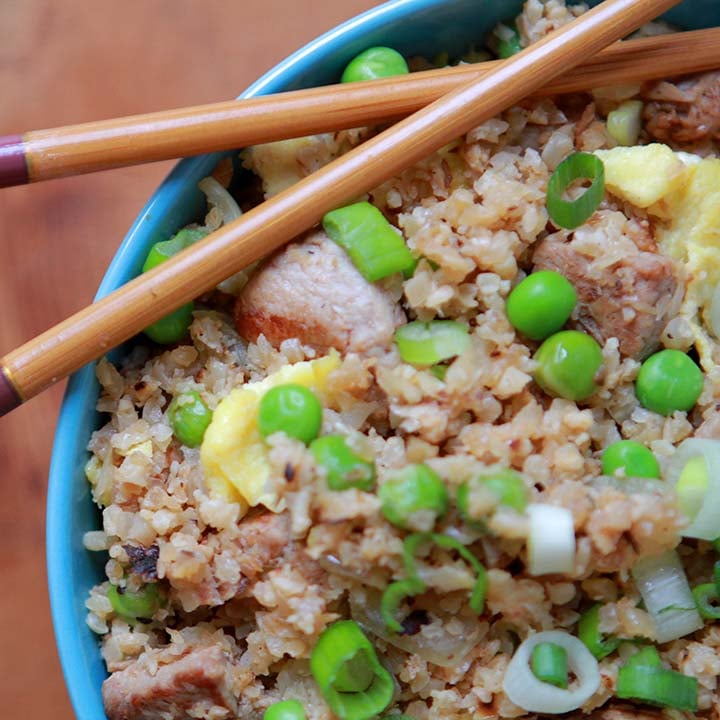 a top down close up of a bowl of healthy pork fried cauliflower rice