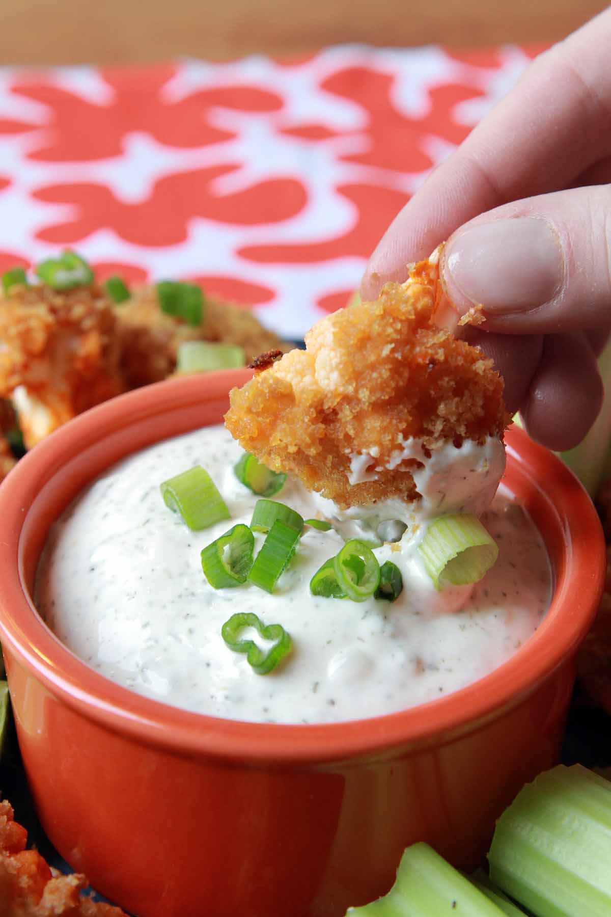 a hand dips a Buffalo Cauliflower Wing into some Ranch Dressing