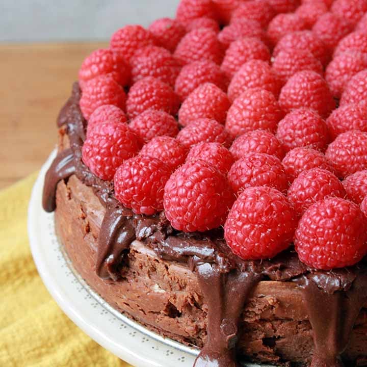 a side view of a Keto chocolate cheesecake with fresh raspberries on top