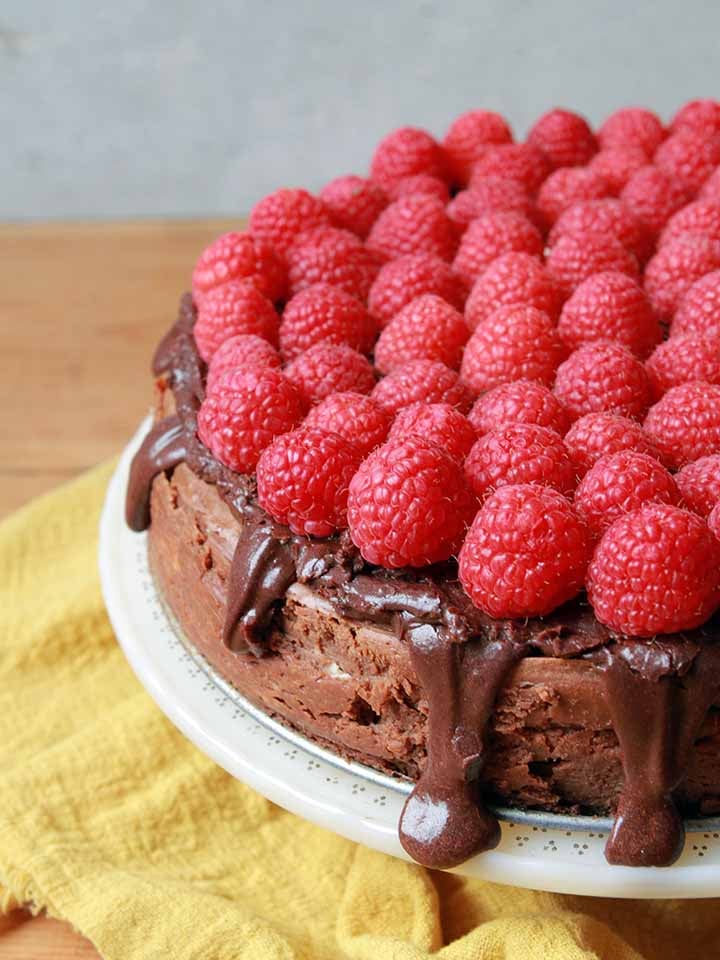 a side view of a Keto chocolate cheesecake with fresh raspberries on top