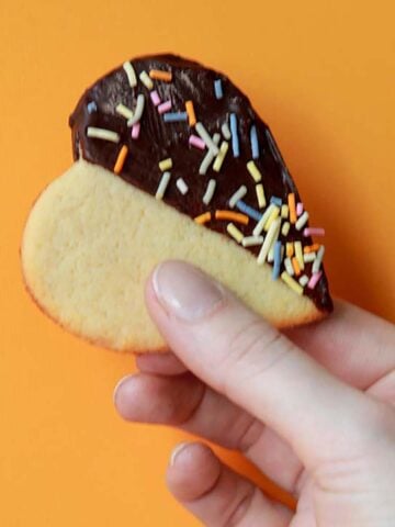 a hand holds a heart shaped Keto cookie