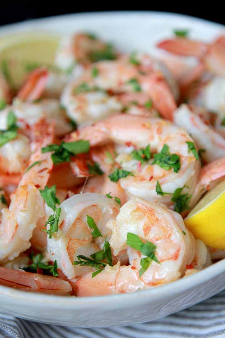 a white bowl filled with sauted shrimp in lemon butter sauce