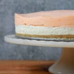 a Keto layered orange creamsicle cheesecake on a pedestal