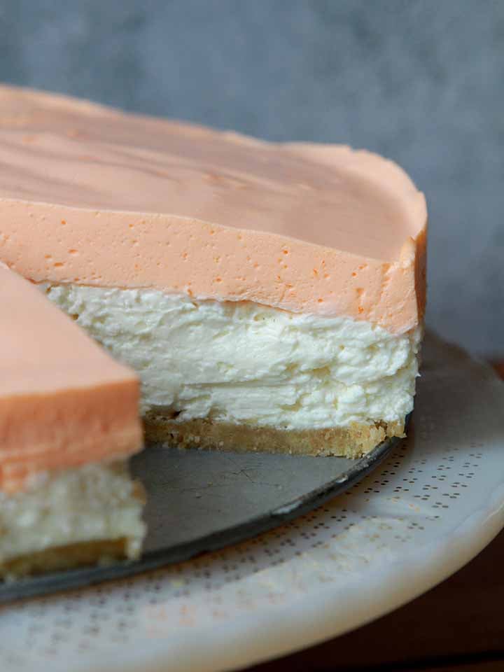 a side view of a Keto orange creamsicle cheesecake on a pedestal