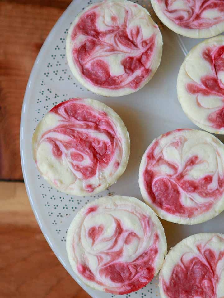 a top down shot of a plate of raspberry swirl mini cheesecakes