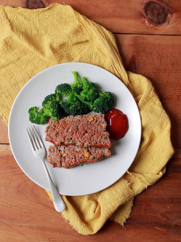 2 slices of Whole30 meatloaf on a plate with broccoli