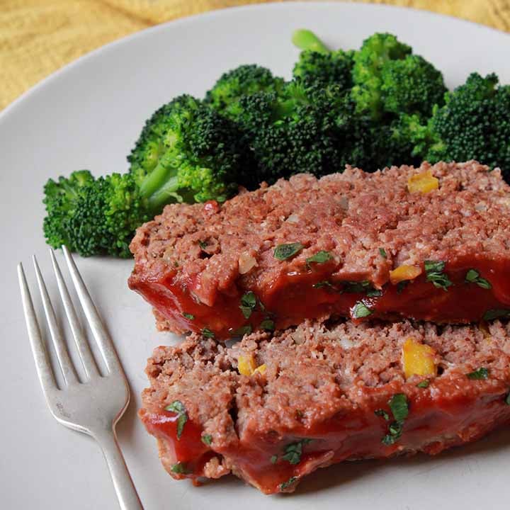 2 slices of Paleo meatloaf on a plate with broccoli