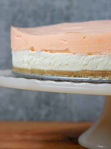 a Keto orange creamsicle layered cheesecake on a pedestal