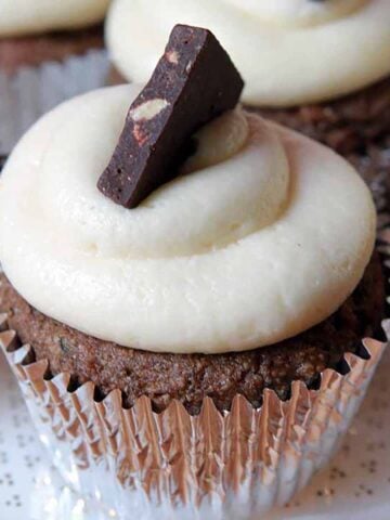 a Keto almond bark topped chocolate cupcake with buttercream frosting