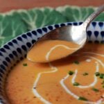 A spoon scoops up a bit of Keto Carrot Coconut Soup