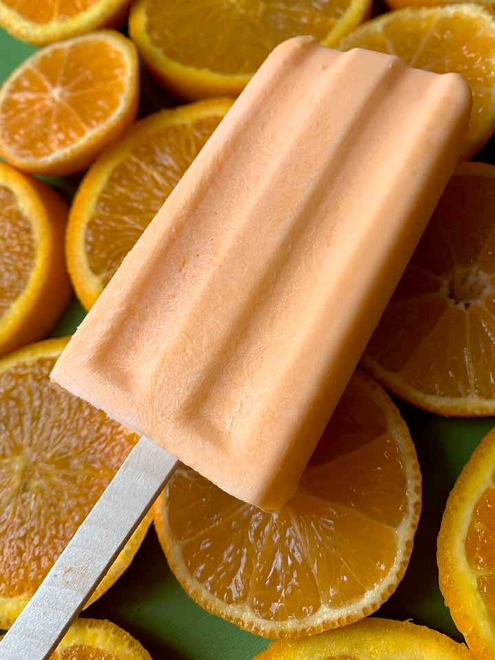 an orange creamsicle against a background of oranges