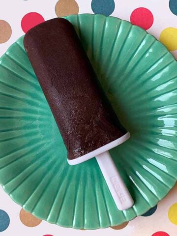 a Keto chocolate pudding pop on a green plate against polka dots