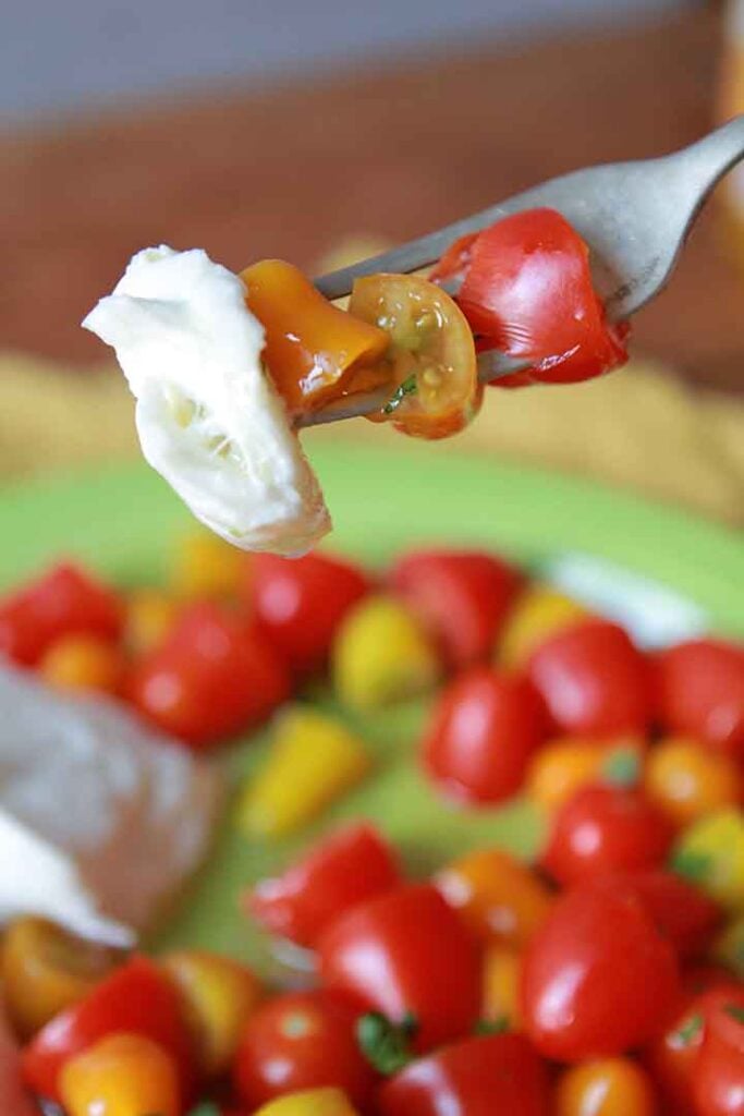 a fork holds a bite of keto mozzarella and tomato salad