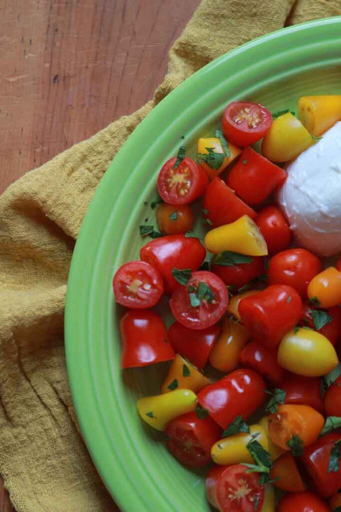 a green plate of cheese and tomato salad