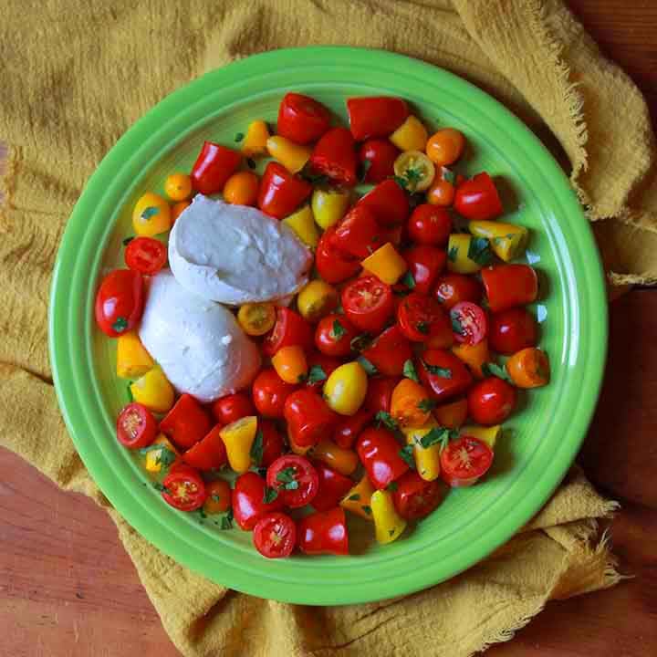 top down view of a green plate with an easy caprese salad