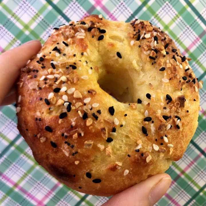 a hand holds a low carb everything bagel