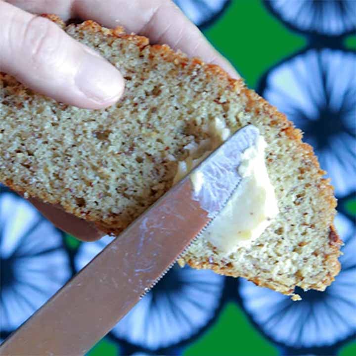 a hand spreads butter on a slice of Keto Yeast Bread