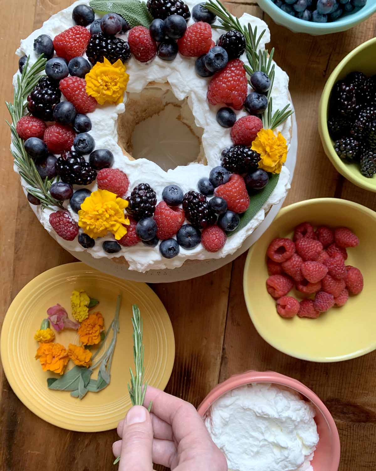 a hand garnishes a Gluten-Free Angel Food Cake