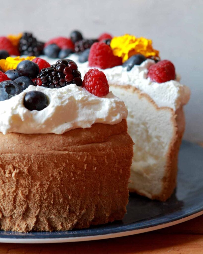 a Keto Angel Food Cake with a slice cut out of it