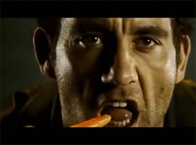 a gif of clive owen angrily eating a carrot