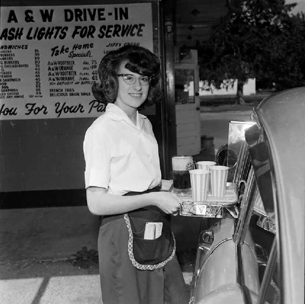 a 1940s car hop bringing food to a car