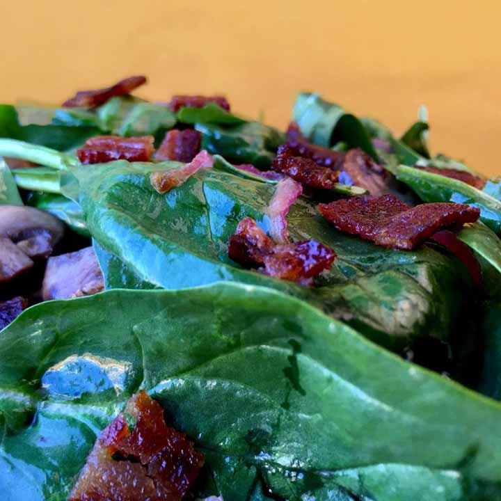 a Keto Spinach Salad against a yellow background