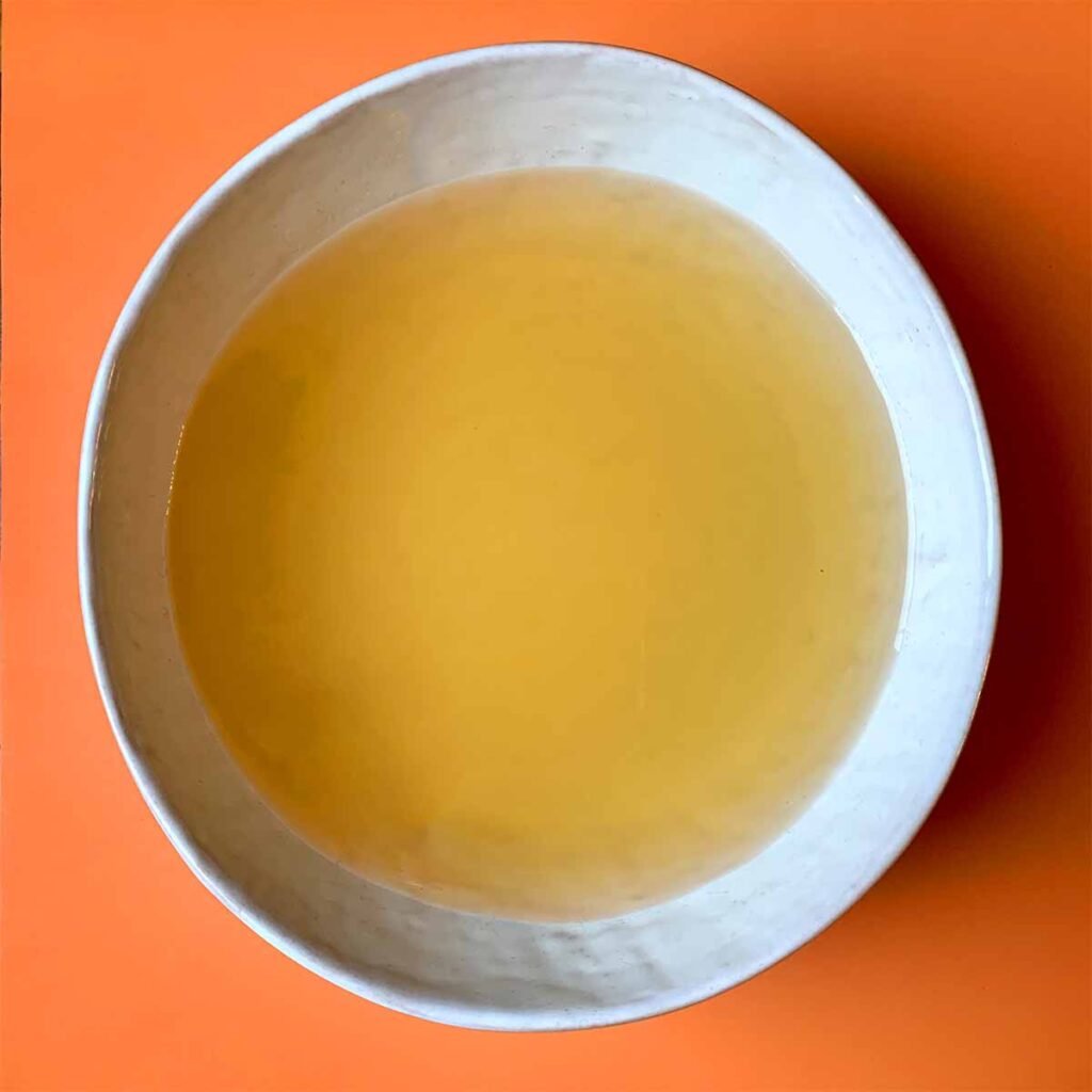 a bowl of bone broth against an orange background. 