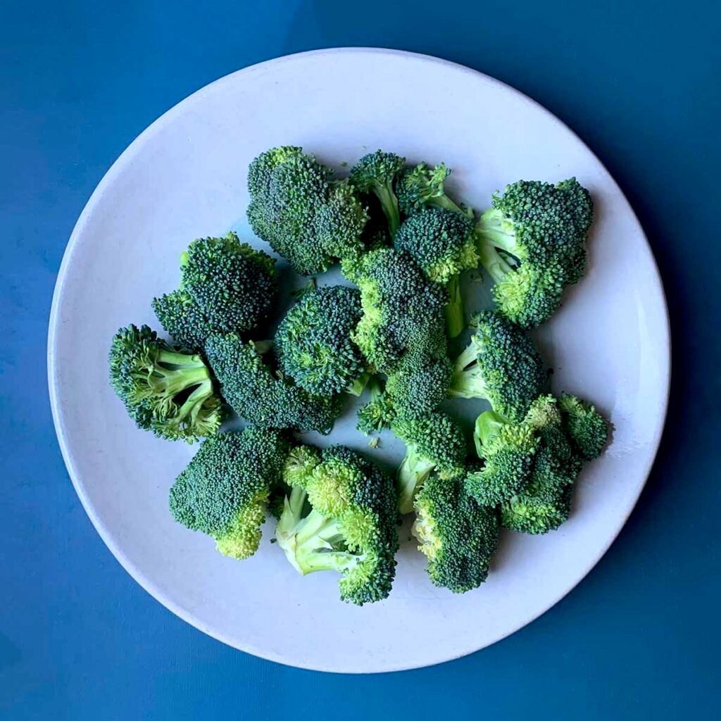 a plate of broccoli against a blue background