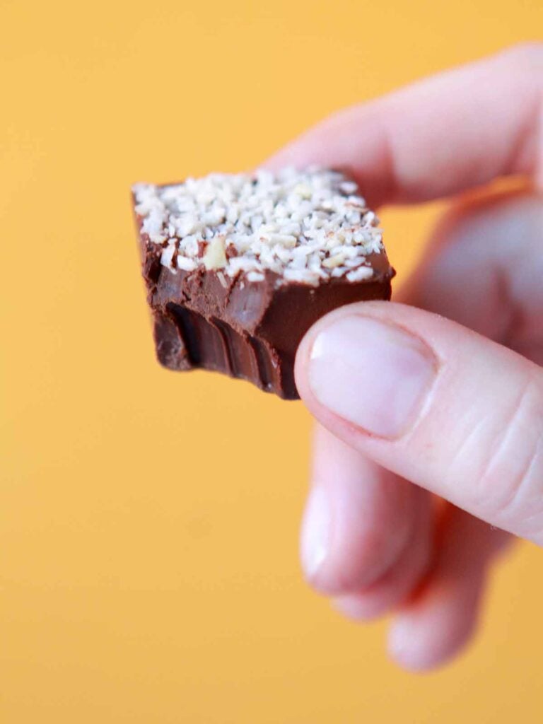 a hand holds a sugar-free chocolate candy with a bite taken out of it