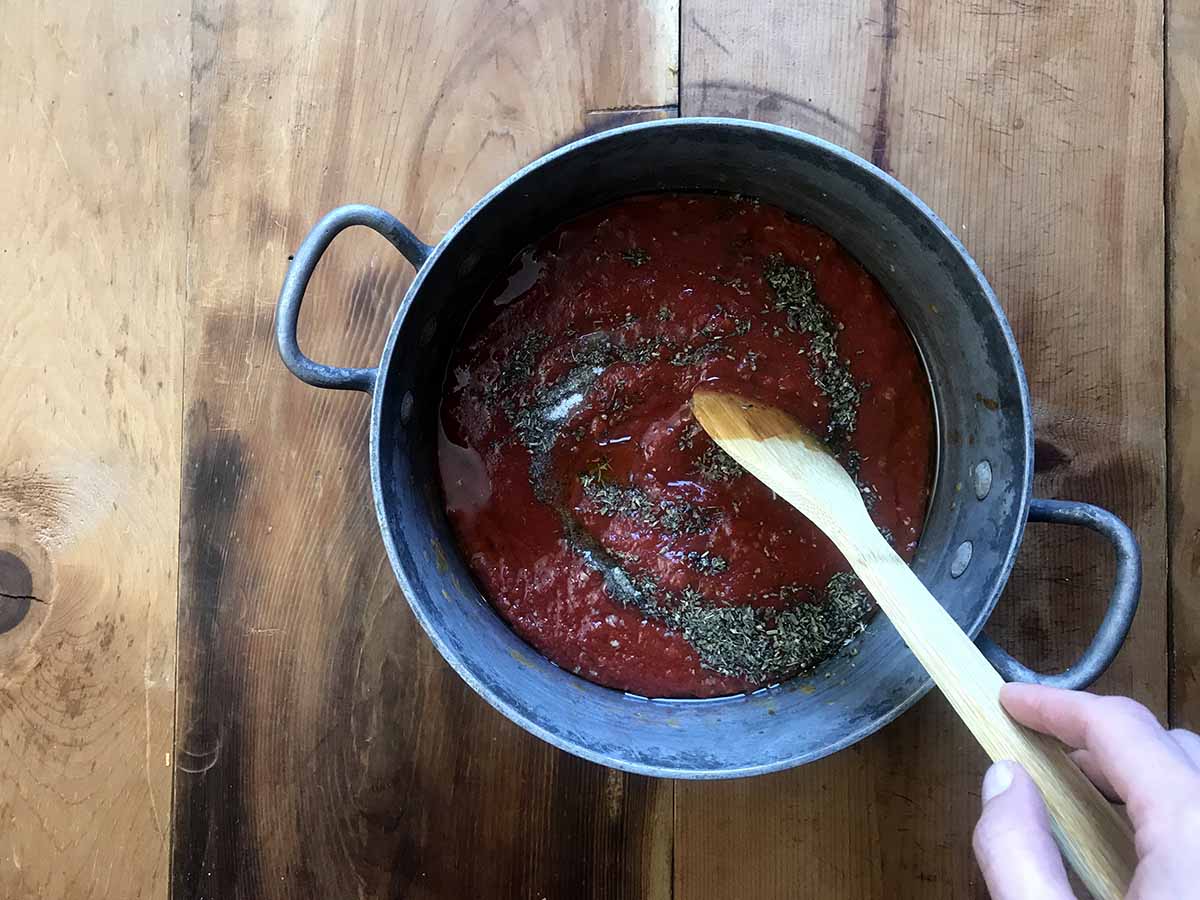 spices being stirred into Keto tomato sauce