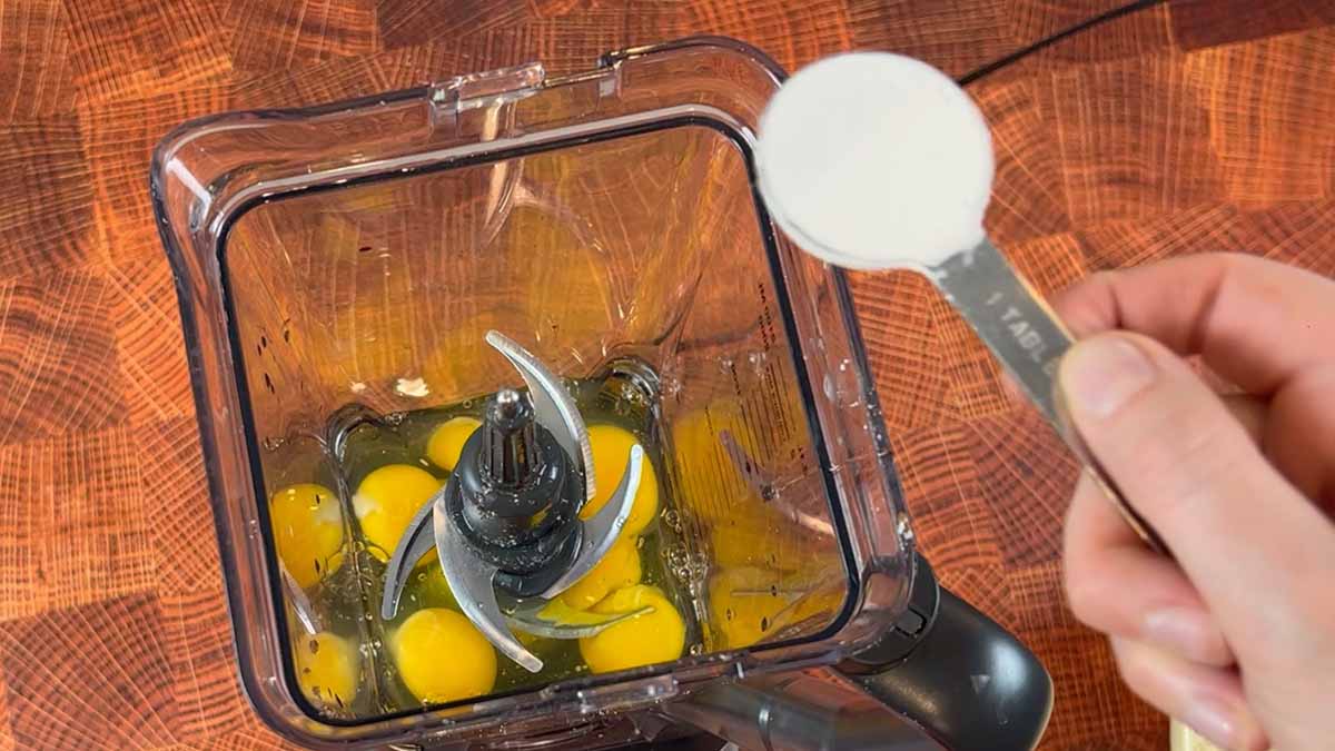 a hand adds ingredients to a blender