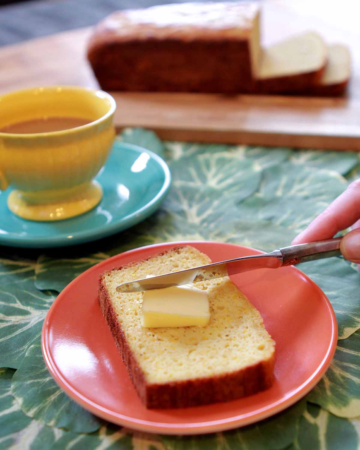 a hand butters a slice of Keto Banana Bread