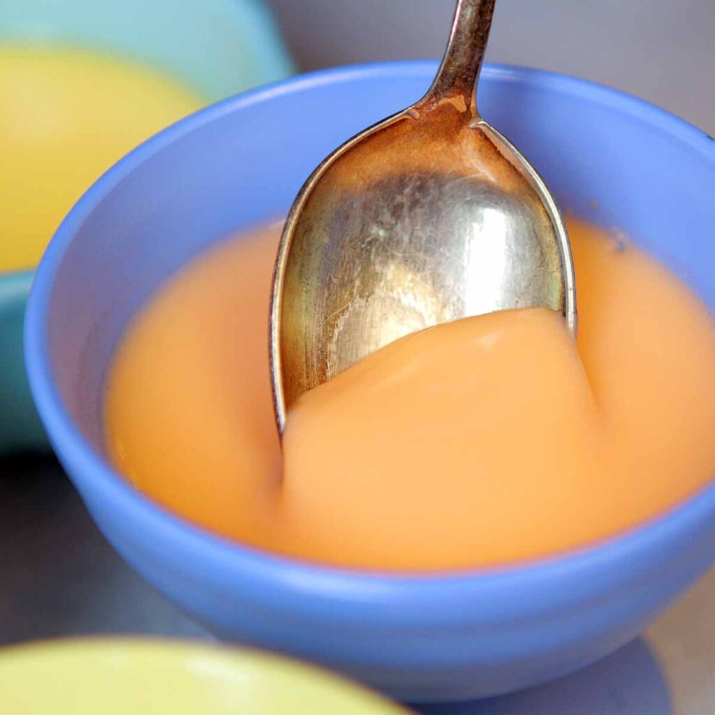 a spoon digs into a bowl of low carb yogurt