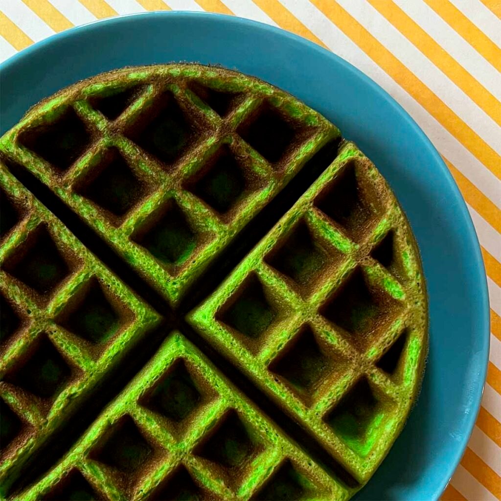 a Pandan Waffle on a blue plate against a yellow striped background